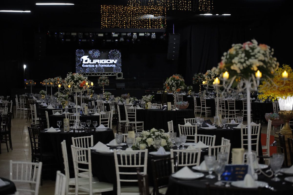 Mesas, candelabros e palco iluminado no baile
